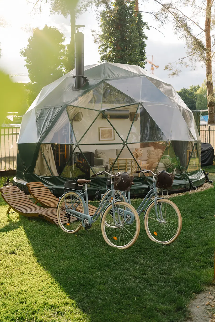 Geodesic dome at golden hour with two vintage bicycles and a wooden lounger in the garden